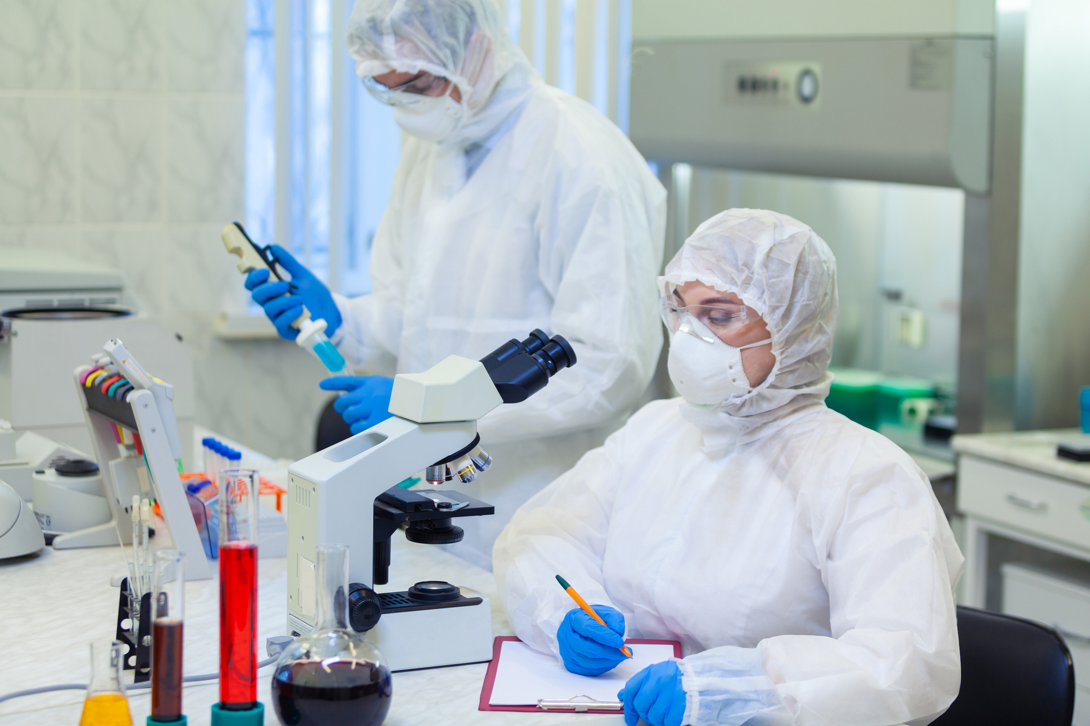 Scientists in protective suits in a science laboratory study a dangerous virus to eliminate the epidemic