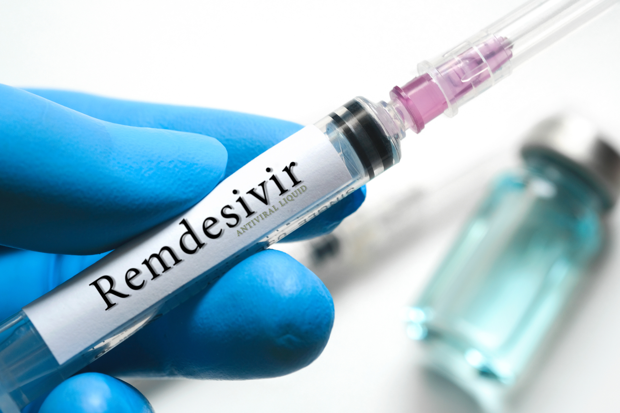 doctor's hand holds a syringe and a blue vaccine Remdesivir bottle at the hospital. Health and medical concepts