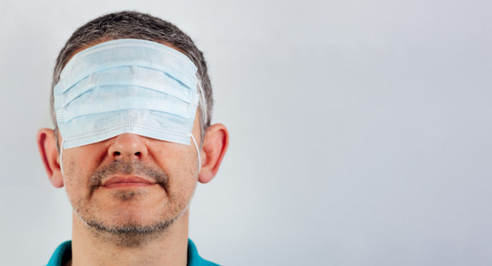 isolated blindfolded man with surgical mask over the eyes