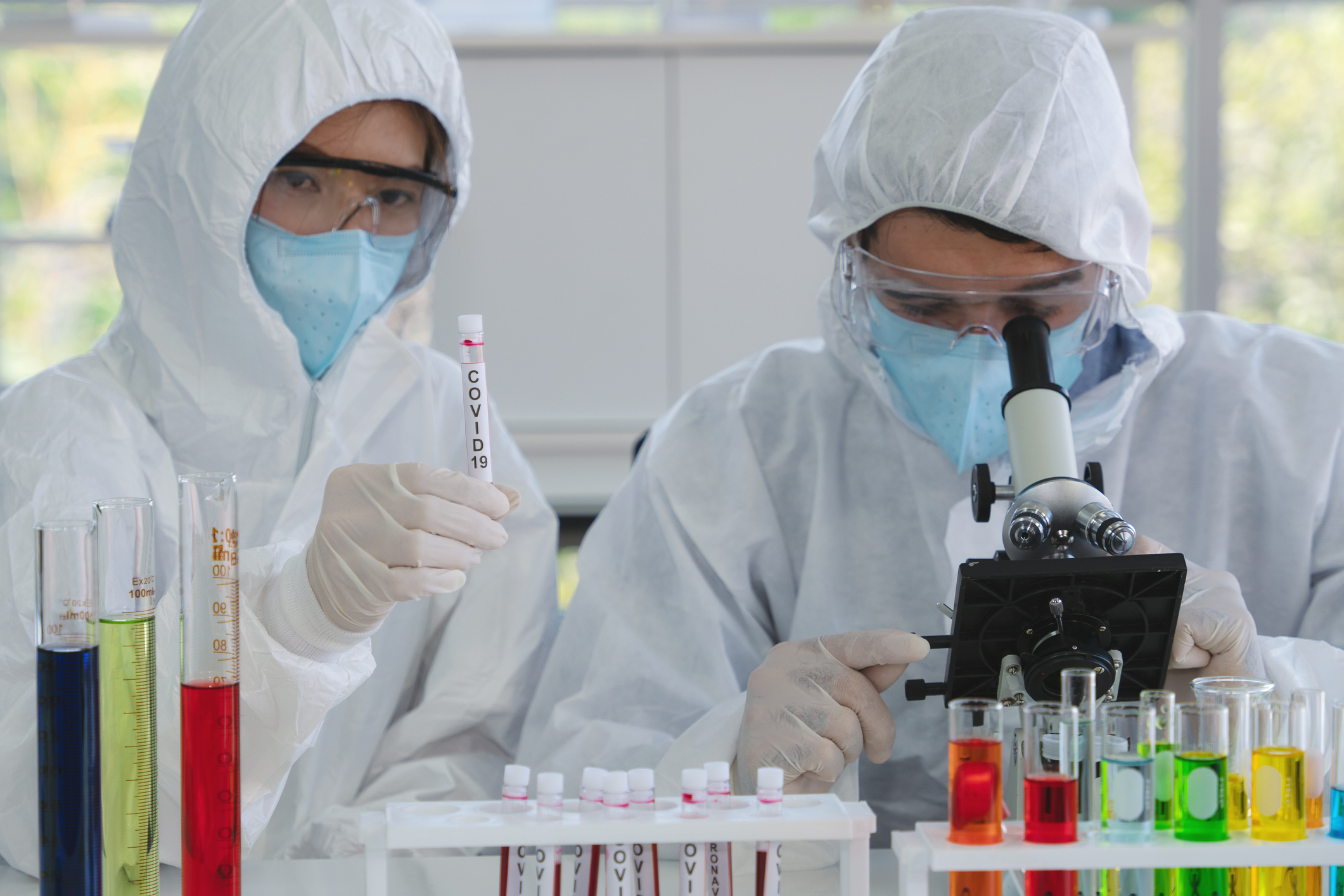 coronavirus covid-19 infected blood sample in sample tube on hand of scientist in biohazard protection clothing doing analysis to virus sample in laboratory
