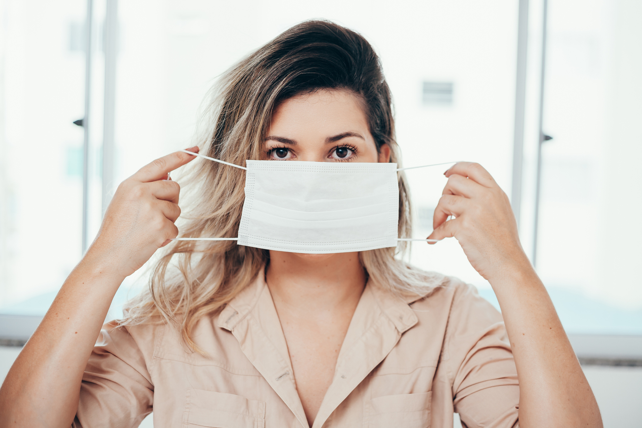 Portrait of woman wearing surgical mask at home. Covid-19, coronavirus and quarantine concept.
