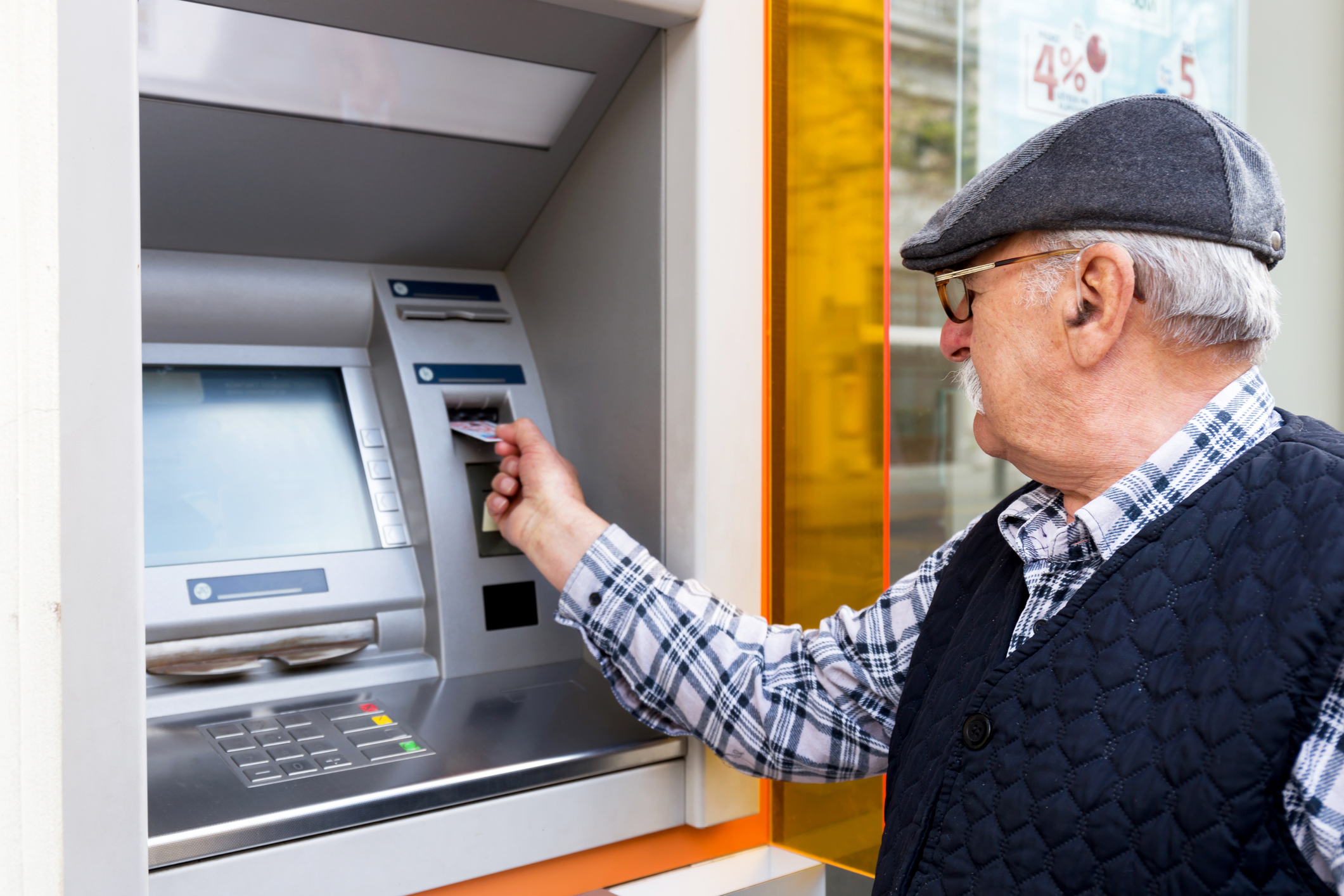 elderly man inserting credit card to ATM farmacias